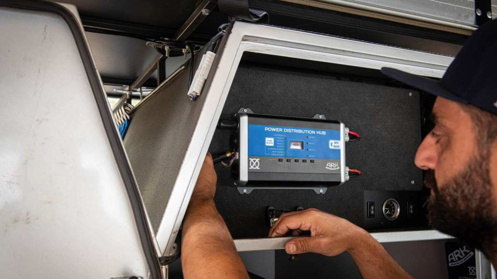 A man installs the 12V XO Power Distribution Hub into his touring ute canopy.