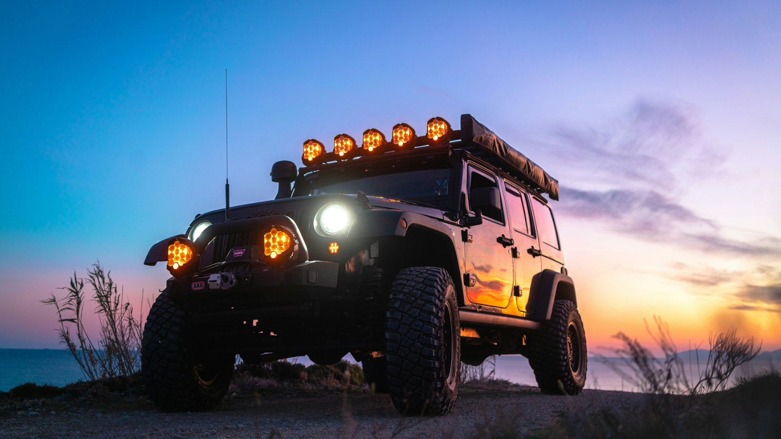 4x4 off-grid touring rig sits lit up on a ridge at sunset