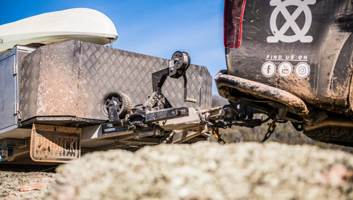 Off-road camper trailer coupling and swing-up jockey wheel hitched to a 4WD tow vehicle.