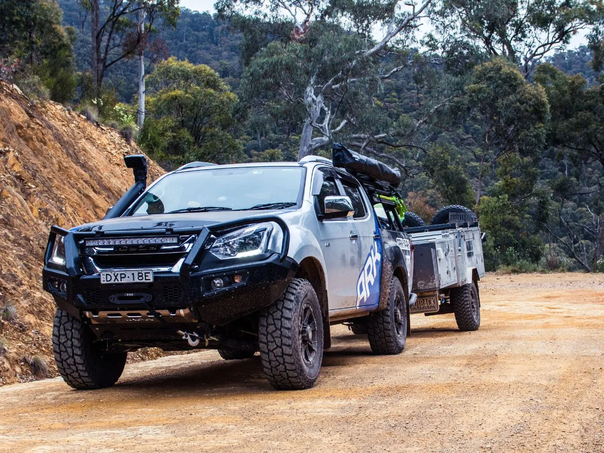 4WD towing a trailer along a dirt track in the Australian bush.